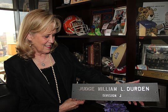 Circuit Judge Mallory Cooper holds a nameplate belonging to her father, former Judge William Durden. Cooper can't hang it in her office because the divisions are different, but she keeps it tucked inside a display case behind her desk.