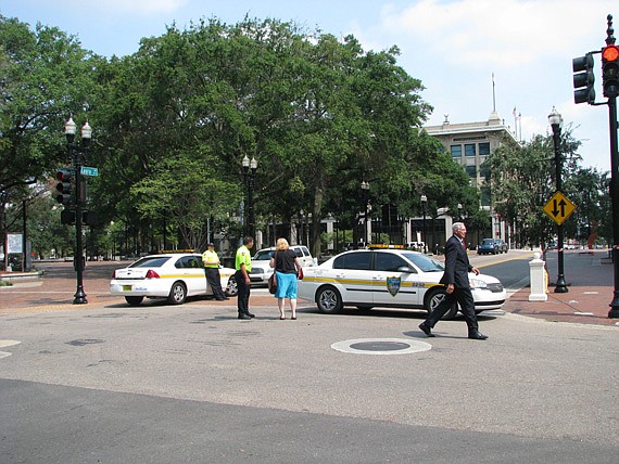 Photos by Joe Wilhelm Jr. - U.S. Bankruptcy Chief Judge Paul Glenn (right) walks to The Jacksonville Bar Association meeting Tuesday at the Downtown Library as the Jacksonville Sheriff's Office kept the public at a safe distance from City Hall after a...