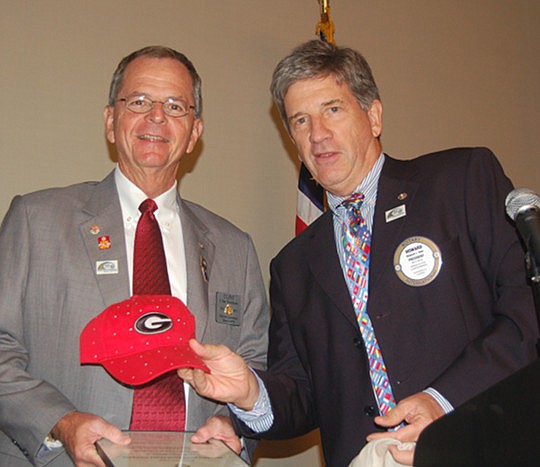Photos by Max Marbut - Rotary District 6970 Governor Clint Dawkins (left) and Rotary Club of Jacksonville President Howard Dale, who presented Dawkins, a University of Georgia alumnus, with a UGA cap.
