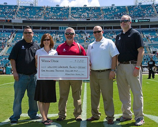 Before the kickoff at the Sept. 11 Jacksonville Jaguars vs. Tennessee Titans game at EverBank Field, Mary Kellmanson, Winn-Dixie group vice president of marketing (second from left) presented a check for $100,000 to Wounded Warrior Project alumni (lef...