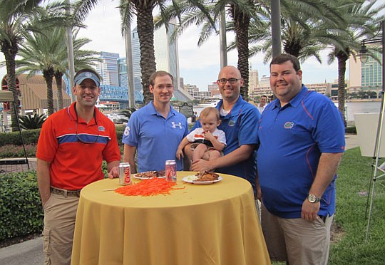 (From left) Javan Grant and Steve Kelly, attorneys at Rogers Towers, along with with Akerman Senterfitt attorneys David Applegate (holding son, Tig) and Chris Garrett enjoyed an afternoon of barbecue, games of skill and live music at the 10th Annual P...