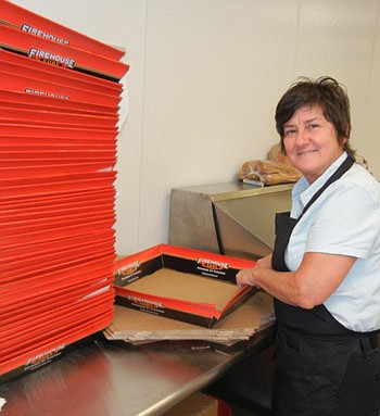 Photo by Karen Brune Mathis - Cindi Ross assembles platter boxes for donated Firehouse Subs to runners in Saturday's Festival of Lights Jingle Bell run. Firehouse employees made 95 platters, containing 475 subs, over the weekend.