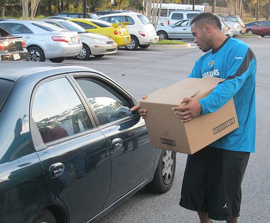 Photos by David Chapman - Jaguars running back Rashad Jennings holds a box of holiday food to load into a car Tuesday at the NFL Youth Education Town in Brentwood. The event marked the third year the team has helped families in need during the holidays.