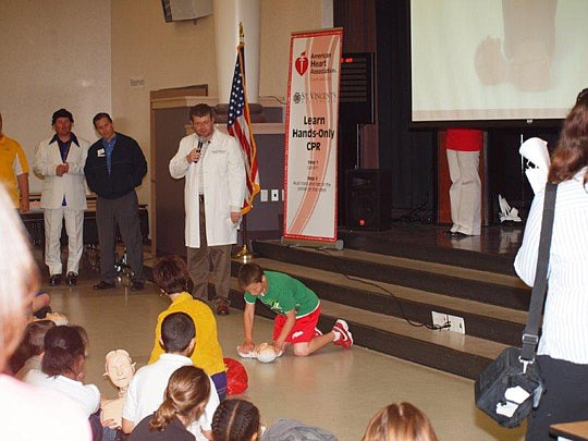 Dr. Matthew Braddock, family medicine resident at St. Vincent's HealthCare, looks on as Turner Pillsbury practices "Hands-Only CPR." Read the story below.