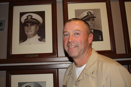 Photo by Joe Wilhelm Jr. - Capt. Robert "Bob" Sanders is the latest base commanding officer for Naval Air Station Jacksonville, relieving Capt. Jeffrey Maclay Jan. 13. Sanders stands near a picture of Capt. Charles P. Mason, the first commanding offic...