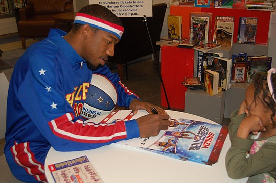 Photos by Max Marbut - Harlem Globetrotter Buckets Blakes signed posters for fans Monday at the Main Library Downtown. His visit was part of the advance promotion for the team's exhibition Friday at Veterans Memorial Arena.