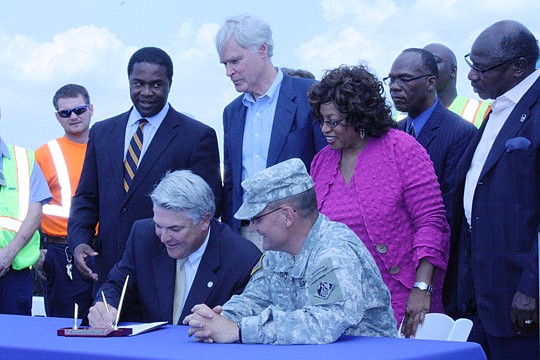 Photos by Joe Wilhelm Jr. - Jacksonville Port Authority CEO Paul Anderson signs the design agreement as (from left) Mayor Alvin Brown, U.S. Rep. Ander Crenshaw, U.S. Rep. Corrine Brown, port board Chairman Reginald Gaffney and ILA South Atlantic and G...