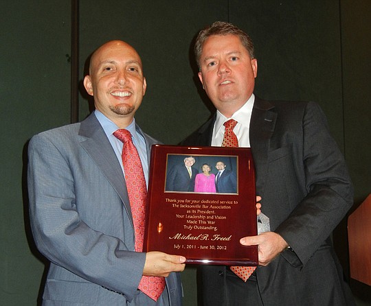 Photos by Karen Brune Mathis - Michael Freed (left) was recognized for his service as the 2011-12 president of The Jacksonville Bar Association with a plaque that features him with his wife, Crystal, and American Bar Association President William Robi...