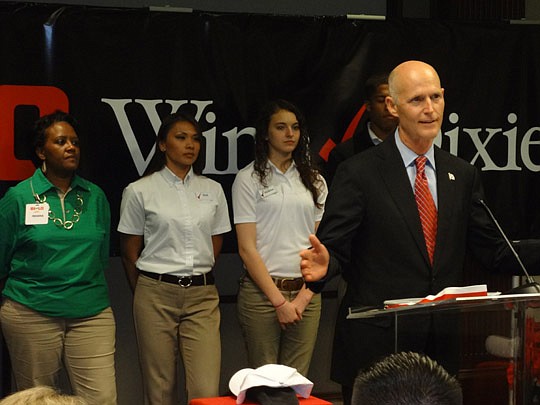 Photo by David Chapman - With employees of supermarket chain Bi-Lo behind him, Gov. Rick Scott announces his intent to double the size of the state's Quick Response Training grant program to $12 million. Last year, the state awarded $5.9 million in gr...