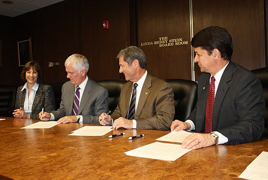 Photo by Joe Wilhelm Jr. - From left, Terri Davlantes, Florida Coastal School of Law vice president of strategy and general counsel, looks on as Florida Coastal Dean Peter Goplerud and Jacksonville University President Kerry Romesburg sign to create a...