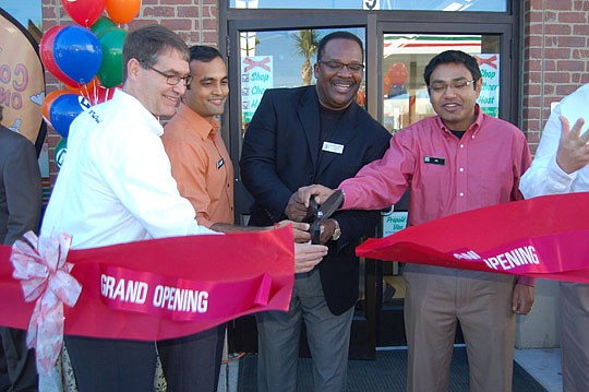Photos by Max Marbut - From left, 7-Eleven North Florida Zone Leader Ben Tison, franchise owner Jay Patel, City Council member Johnny Gaffney and franchise owner Vic Patel cut the ribbon Wednesday to open the 7-Eleven store Downtown at 9 W. Union St. ...