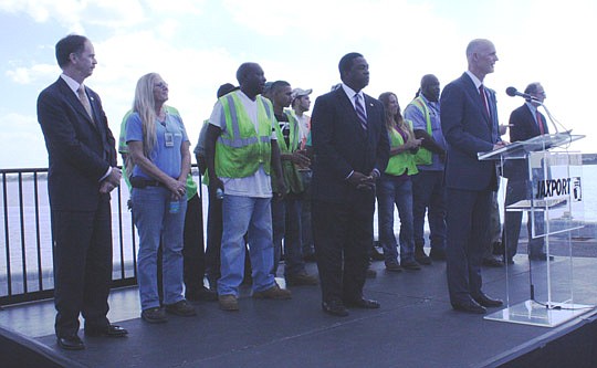 Gov. Rick Scott (right) on Monday discusses investing in Jacksonville's ports to boost Florida's economy. Mayor Alvin Brown (left of Scott) and State Rep. Lake Ray (left) of Jacksonville stand in front of a group of area port employees.