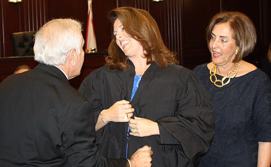 Photos by Joe Wilhelm Jr. - Circuit Judge Tatiana Salvador receives help with her robe from her parents, Dr. Alejandro and Diana Radi, during her investiture Thursday.