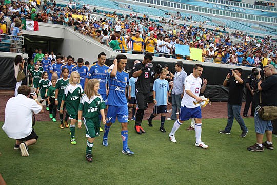 Tigres captain Lucas Lobos (left) and Cruz Azul captain Christian Gimenez lead their teams and players from the Jacksonville Youth Soccer Clubs on Wednesday into EverBank Field for a "friendly" match between Mexico Primera League teams.