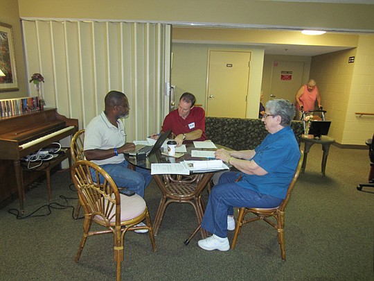 Cecil Grant and Mike Zima assist a resident at PSI Mandarin Center with her advance directives documents.