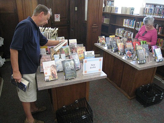 William Pugliese and Sue Culpepper look through books at Willowbranch library on Wednesday. Funding for the branch was restored by the City Council Finance Committee hours earlier.