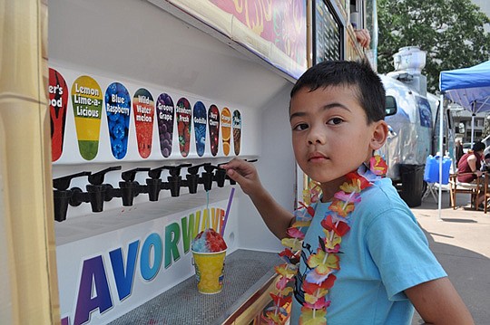 Jonas Cabanban, 7, of Jacksonville, creates a custom Hawaiian shave ice at the Kona Ice truck in the food truck village.