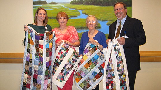 From left, Kim Ely, University of Florida Proton Therapy Institute child life specialist; Bonnie Phillips and Jeanne Huebner, River City Piecemakers Quilt Guild members; and Stuart Klein, executive director of the institute.