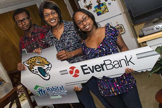 The Finklea family - Marcus, Deborah and Michelle - hold the cardboard key they received during Sunday's Jacksonville Jaguars game. The "key" is for their new HabiJax home they'll be moving into near Edward Waters College.