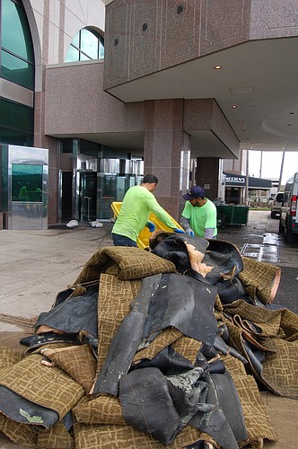 Workers pile soaked carpet Tuesday from inside The Hyatt Regency Jacksonville Riverfront Downtown. (Photo by Max Marbut)