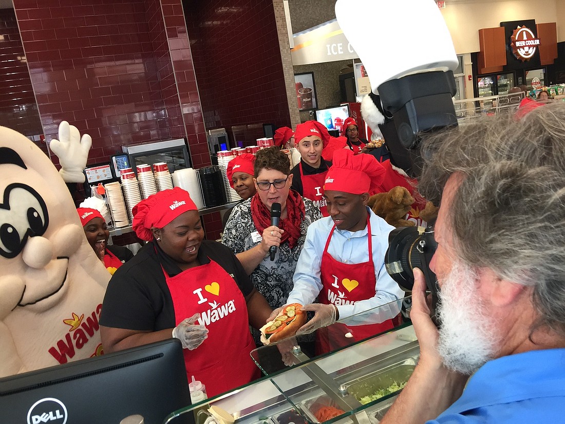 Donna Plant, store manager of the Wawa at 6787 Wilson Blvd., guides City Council member Garrett Dennis to prepare the first hoagie produced at a Jacksonville-area Wawa. The store had a tasting Tuesday in advance of its opening.