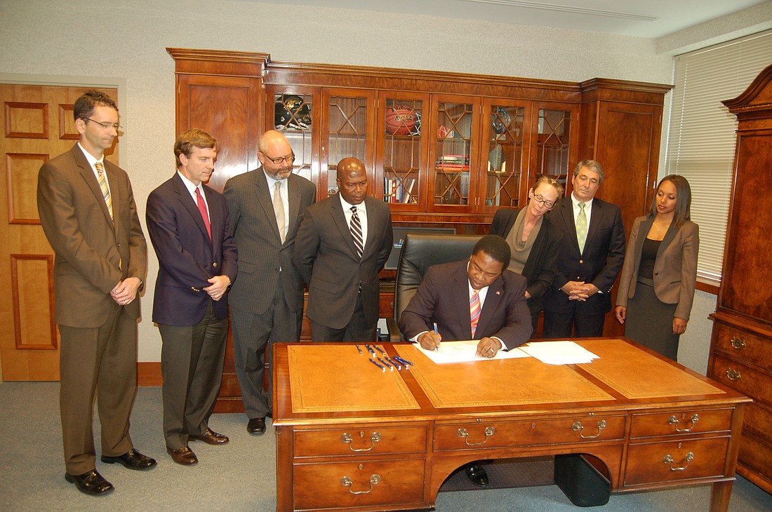 Mayor Alvin Brown signed legislation that authorized the DIA, witnessed by, from left, authority board members Oliver Barakat, Rob Clements, Tony Allegretti, Donald Harris, Melody Bishop, Jim Bailey and Kay Harper.