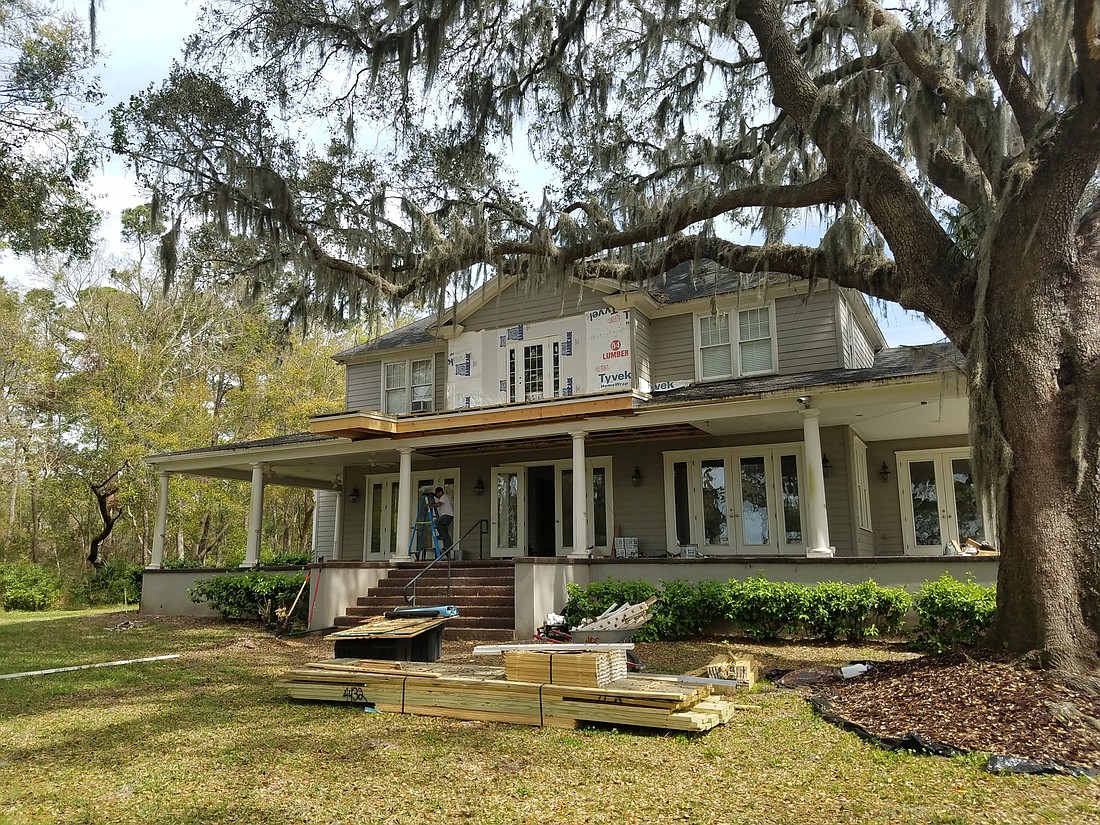 The back of the former Alumni House just north of the Jacksonville University campus features a large covered porch and views of large oak trees and the St. Johns River.
