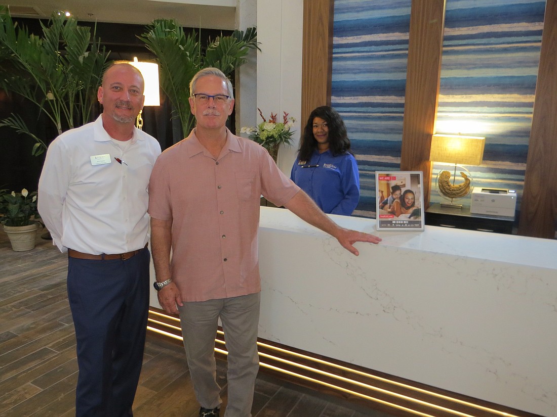 Art Casey (left) and Bernie Moyle at the new front desk at the Lexington Hotel & Conference Center. Waiting to check in guests is Mercedes Roberts.
