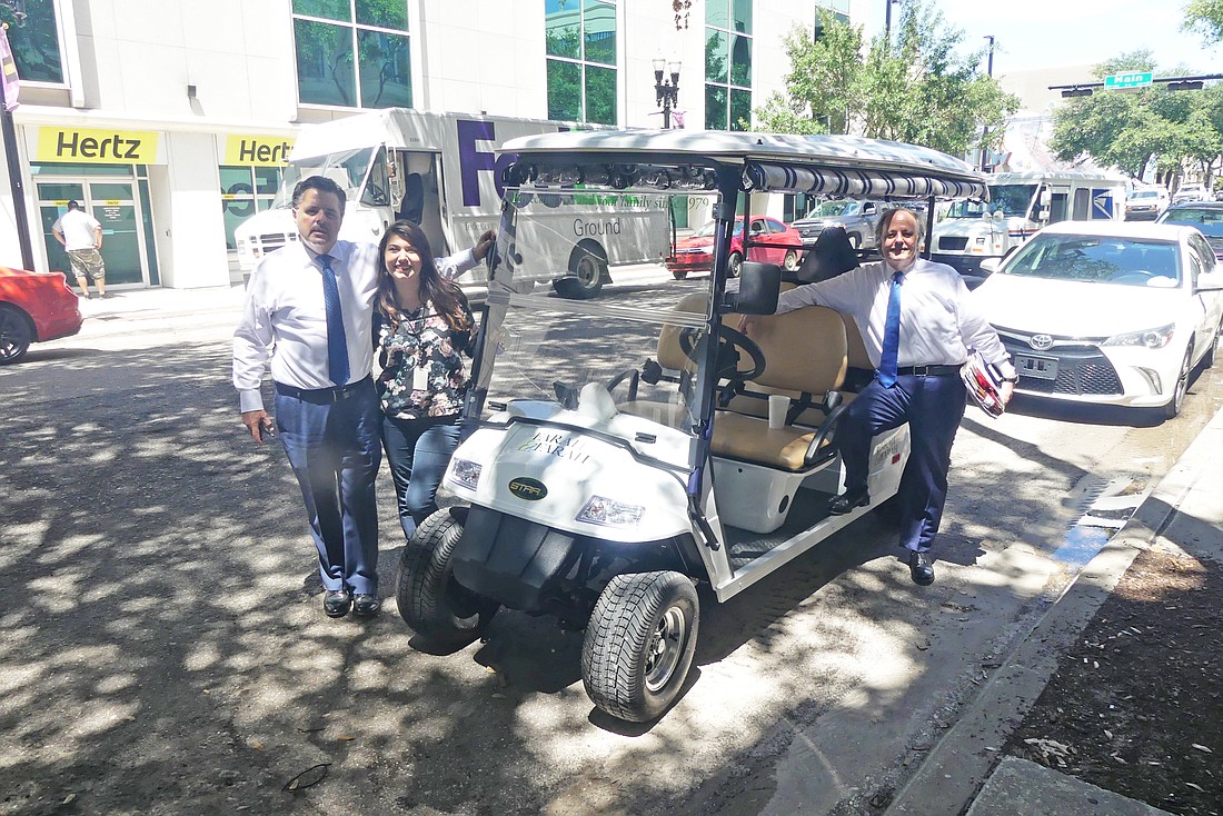 From left, attorney Chuck Farah, Farah & Farah Case Manager Brooke Hazleton and attorney Eddie Farah with the law firmâ€™s new electric vehicle thatâ€™s used to travel between two buildings the firm owns Downtown.