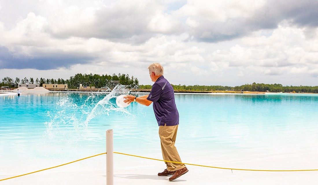 Beachwalk developer John Kinsey throws the final gallon of water into the 14-acre lagoon. Photo by James Brown, Jr./Special to the Daily Record