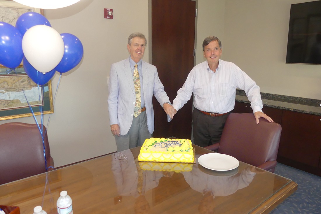 Law partners Michael Fisher, left, and Clay Tousey Jr. cut their firmâ€™s 40th anniversary cake Monday.