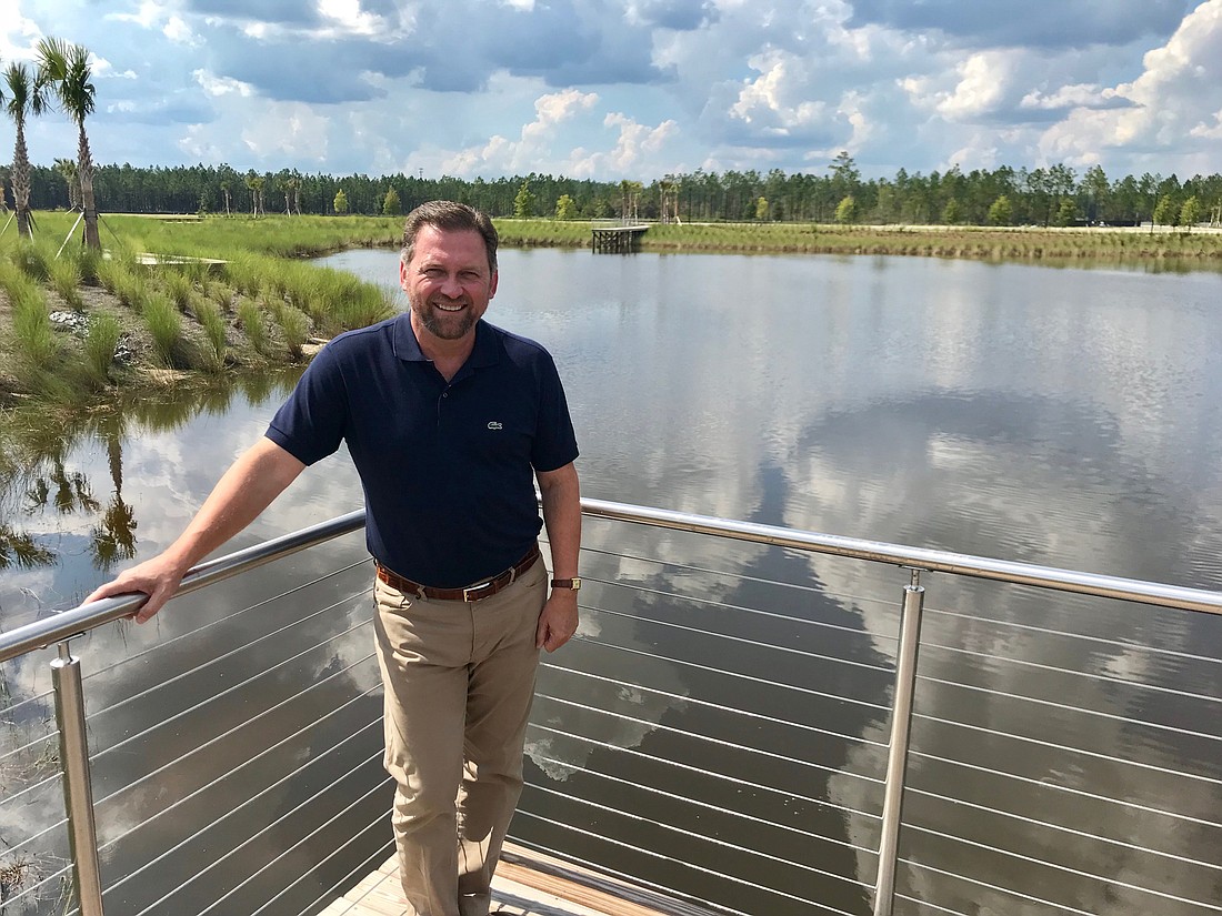 Charles Adams, vice president of community development for Raydient Places + Properties, stands on a dock by a pond in the Wildlight community in Nassau County.