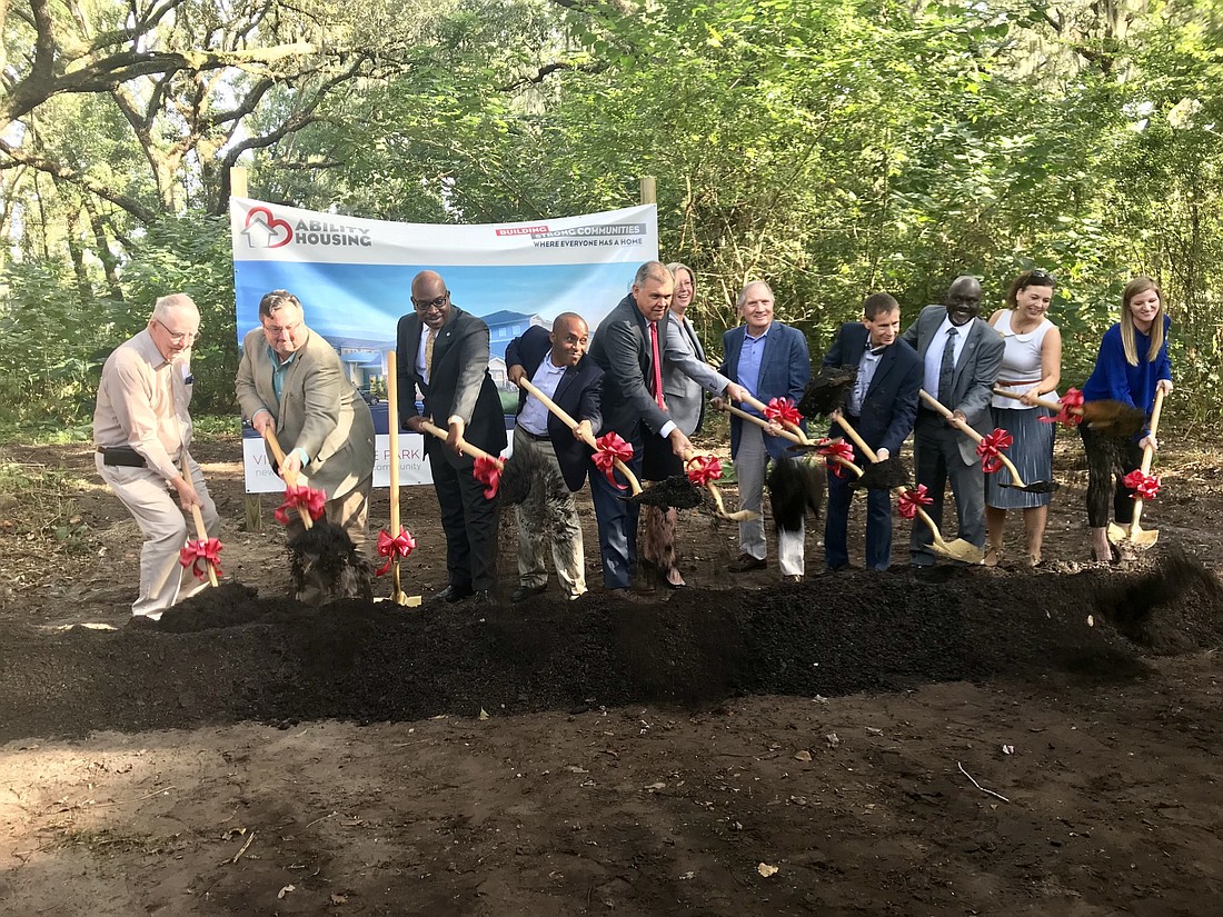 Ability Housing representatives, local elected officials and other community leaders toss a shovel full of dirt as part of the traditional groundbreaking ceremony at the site of what will be Village at Hyde Park.