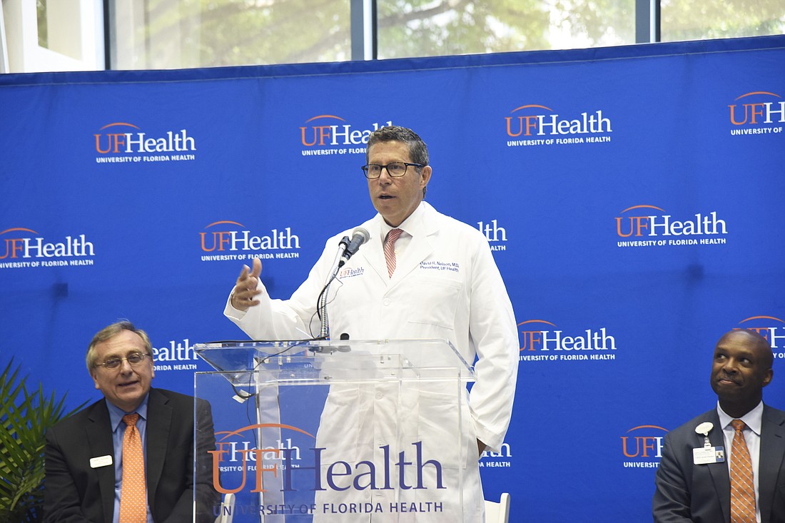 Dr. David Nelson addresses UF Health faculty, staff and students Wednesday at UF Health Jacksonville. At left is UF President Ken Fuchs Nelson and at right, CEO Dr. Leon Haley.