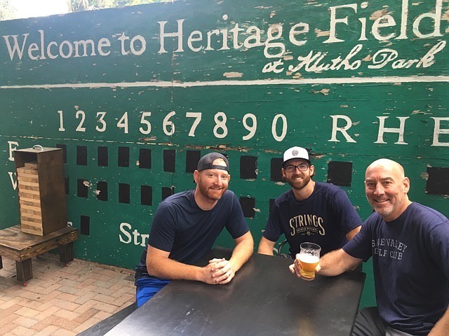 Trevor, Colby and Scott Adeeb sit in the beer garden at Strings Sports Brewery in front of the baseball scoreboard salvaged from from Klutho Park. They are partners in the venture. (Photos by Dan Macdonald)