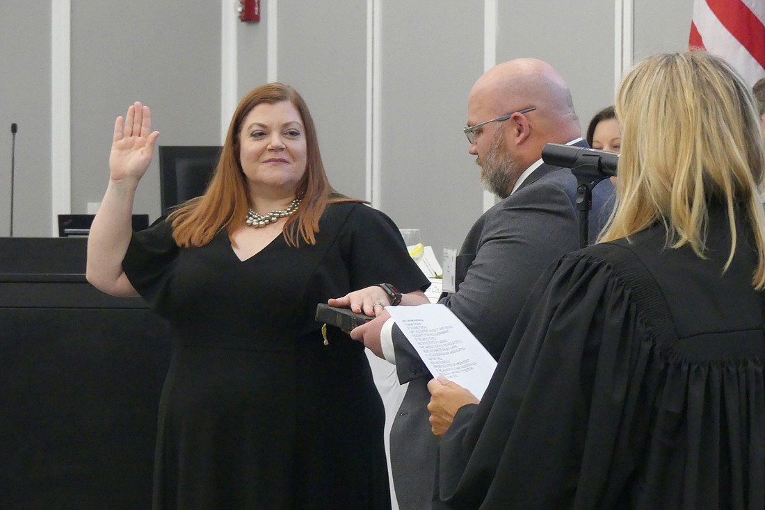Elizabeth Ferguson is sworn in as 2019-20 president of the Jacksonville Bar Association by Circuit Judge Katie Dearing with Fergusonâ€™s husband, Steve, holding the Bible.