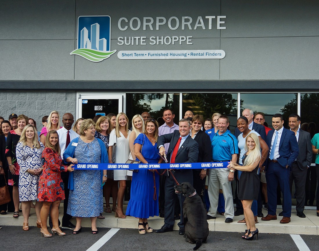 Corporate Suite Shoppe President Bryan Davis cuts the ceremonial ribbon at 8200 Cypress Plaza Drive with his wife, Tiffany, company employees and guests.