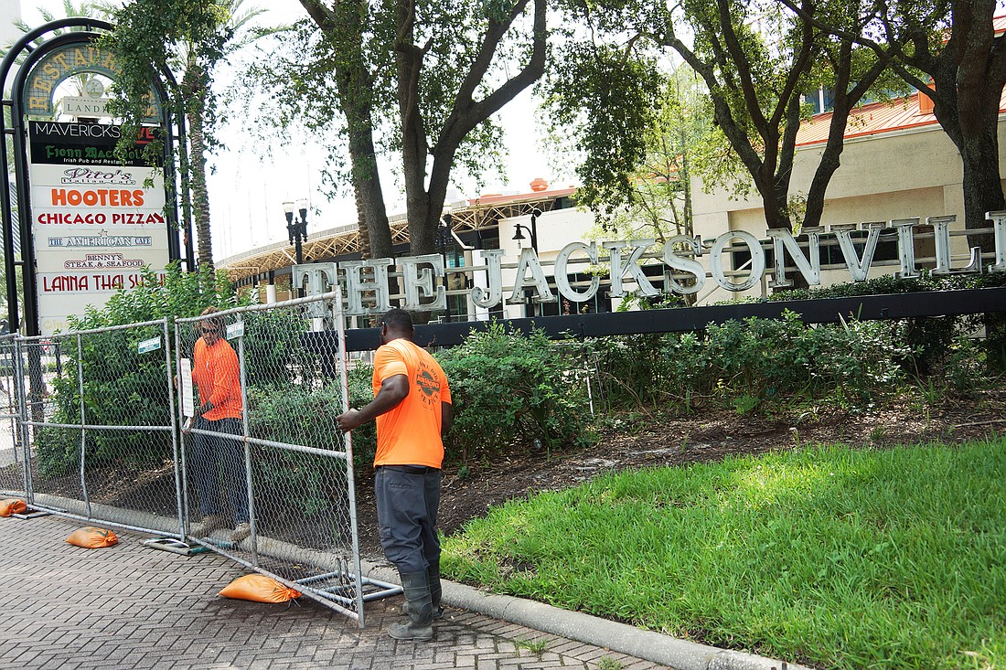 Armstrong Fence Co. workers put up barriers Thursday around The Jacksonville Landing.