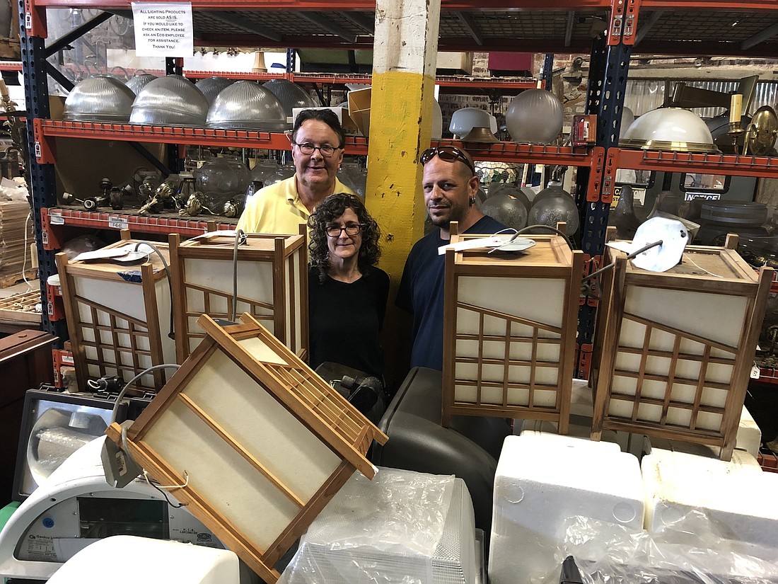 From left, Eco Relics owners Michael and Annie Murphy and manager John Cooper with light fixtures salvaged from The Jacksonville Landing.