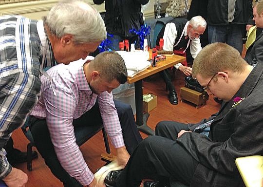 Tim Tebow shines the shoes of a guest at Night to Shine. (Photo from people.com)
