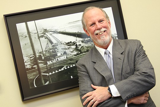 Attorney Gene Atwood stands in his firm's conference room in front of a historic photo of construction in Mandarin.