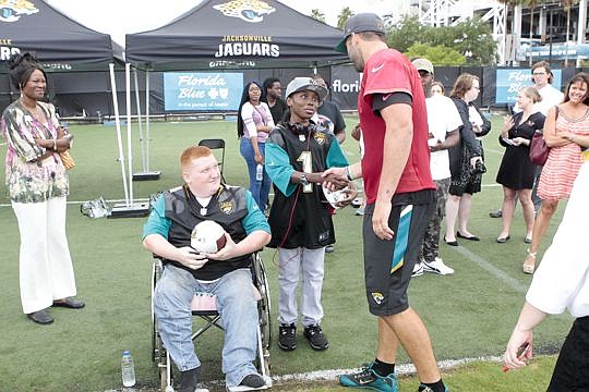 Quarterback Blake Bortles shakes hands with Quinnell Brown as Tristan looks on during a break from the Jaguars' Organized Team Activities.