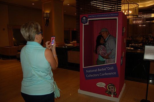 Beth Clarke from Chicago takes a picture of Rosa Linda Claudio and James Laform from San Antonio in the "Barbie Box" at the Hyatt Regency Jacksonville Riverfront. They are among 800 people attending the 2016 National Barbie Collectors Convention that ...