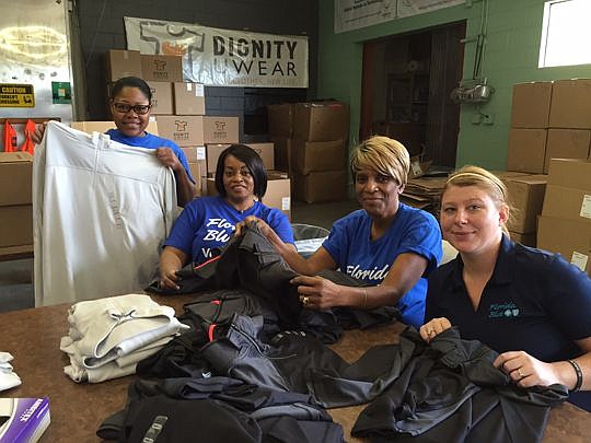 Volunteers from Florida Blue sort clothing at Dignity U Wear. The organization is kicking off its back-to-school campaign.