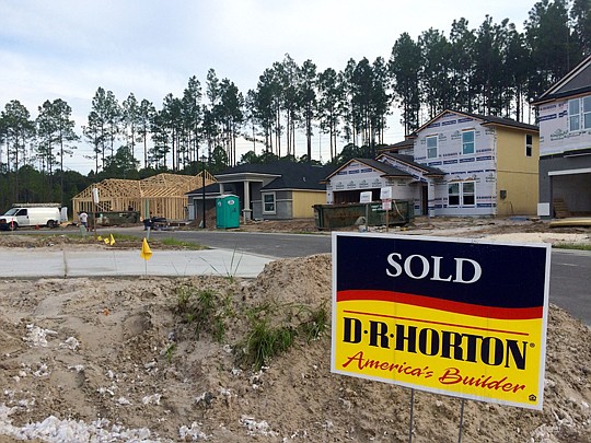 A sold sign in front of a D.R. Horton home as workers finish framing a house in Northwest St. Johns County. Crews are working overtime to keep up with the demand for new housing the area.