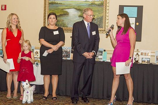 Lindsay Tygart, right, introduces Florida Coastal School of Law President Dennis Stone during the Christian Winicki scholarship fundraiser as part of the school's Founders Day weekend. Also pictured are Chelsea and Kiely Winicki, wife and daughter of ...