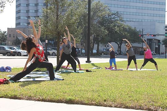 With the weather shifting from sweltering to tolerable in the midday, Circuit Judge Eleni Derke, left, brought back monthly yoga lessons to the front lawn of the Duval County Courthouse. The return on Friday, however, was led by her sister, Bonnie Dav...