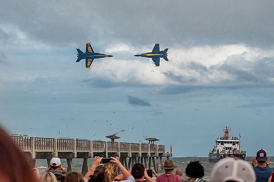 A crowd of spectators cheer and take pictures of two Blue Angels as the planes meet over the Jacksonville Beach pier Sunday, part of the Sea and Sky Spectacular.