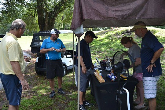 Taking advantage of the rain delay are Jack Dunham, Eddie Gay and Mike Bianchi as they check out the products at the AA Bottle Gas booth with Kimberly Knowles and Todd Knowles.