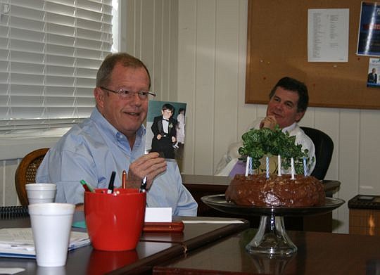 Sales agent Bart Colbert holds up the birthday card he received from the Norville Real Estate team during a sales meeting. Broker-owner Lee Norville is at right.